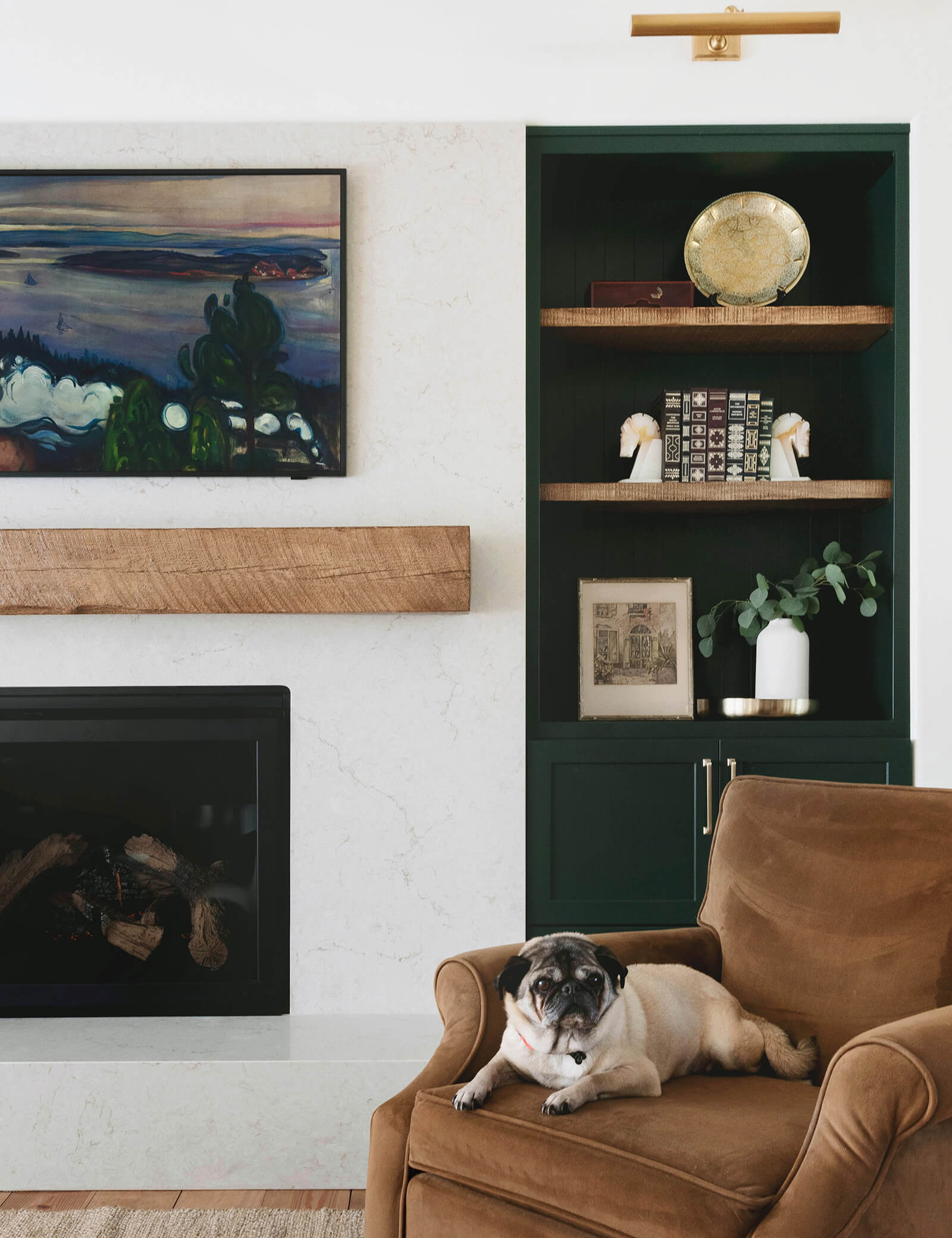 A beautiful livingroom design with dark green painted cabinet built-ins, raw, wood details, and warm decor. Featuring a cute pug enjoying the new remodeled space.