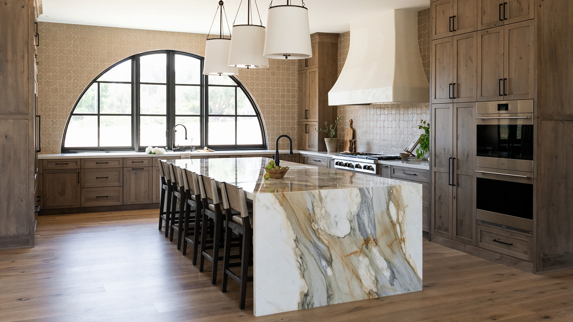 A beautiful nature-inspired kitchen with Mediterranean style and medium stained knotty alder cabinets with.