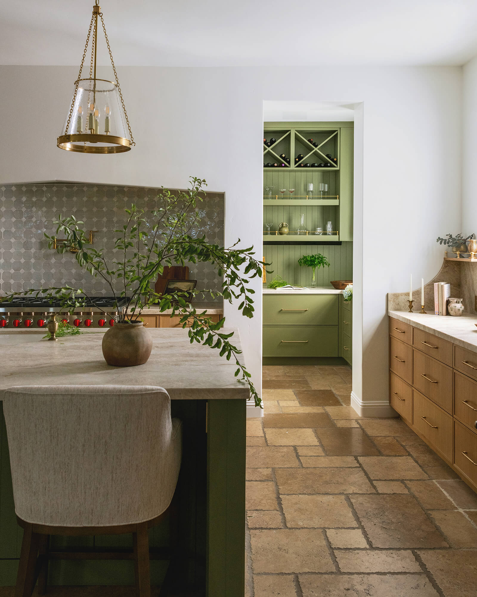 A stunning kitchen with a combination of green painted and natural stained wood cabinets with an earthy, nature-inspired atmosphere.