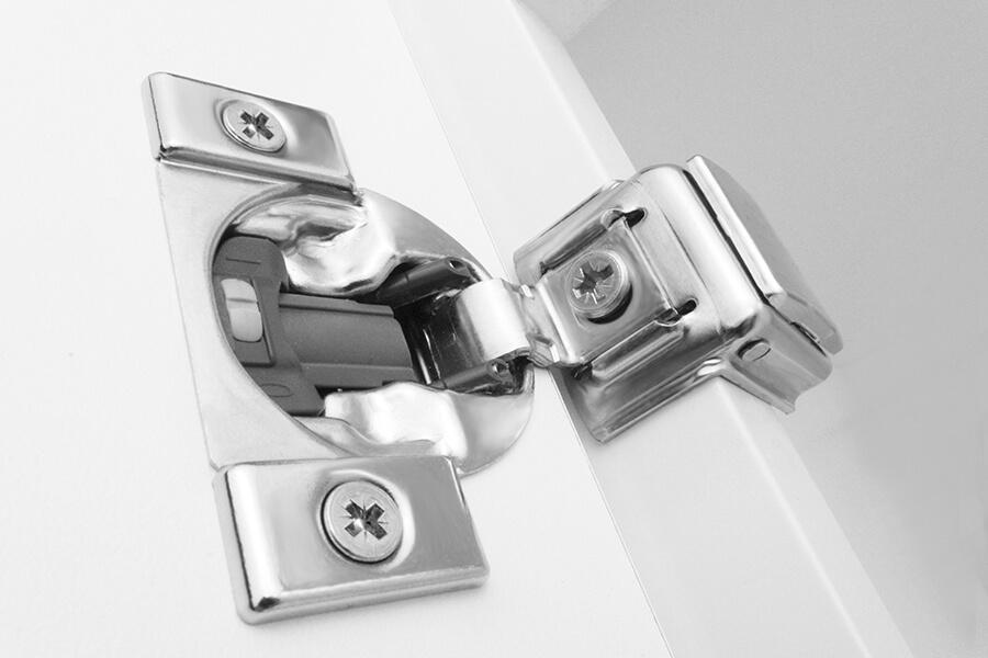 A close up of a premium cabinet door hinge with soft-close on a classic cabinet door from Dura Supreme.