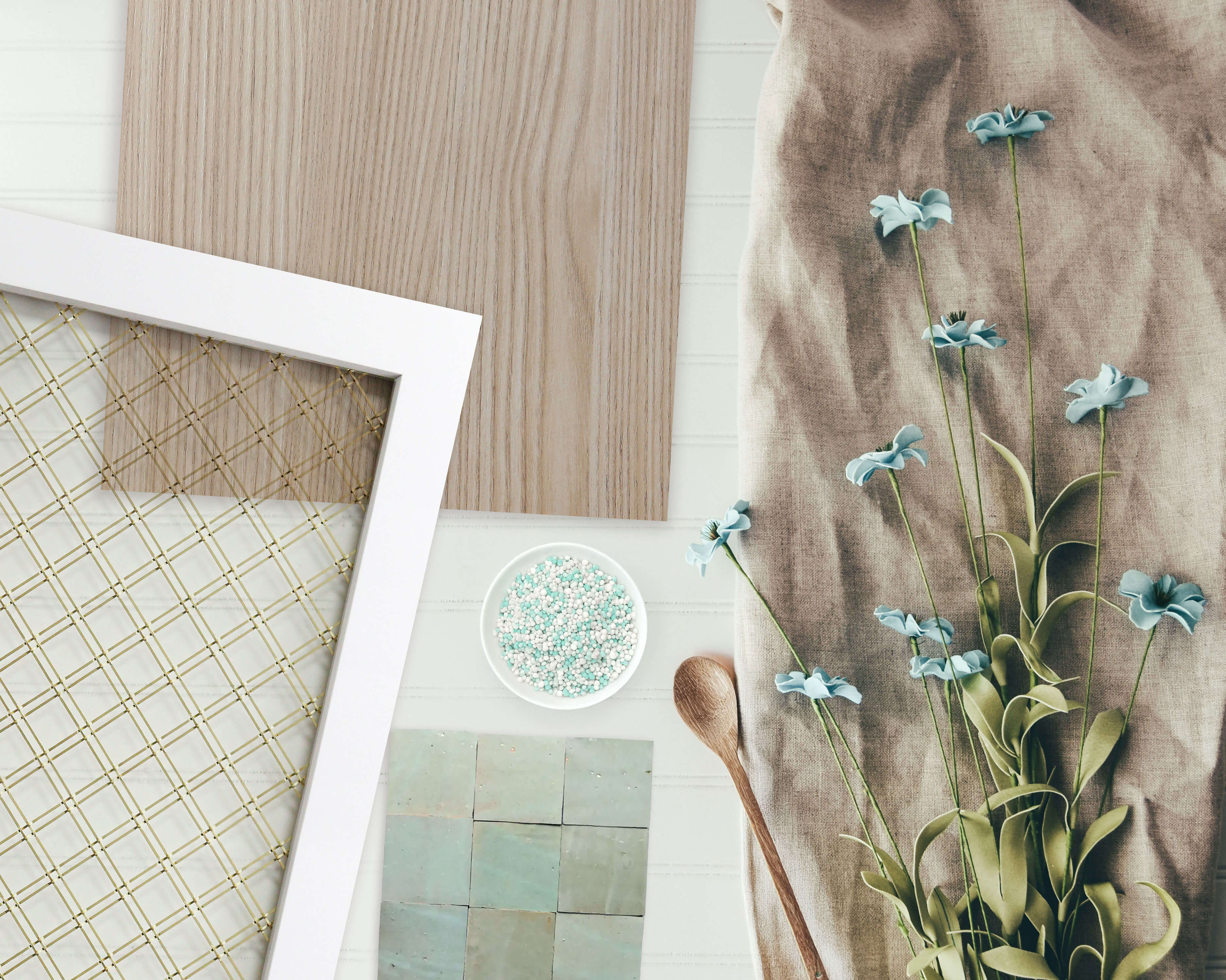 This wire mesh cabinet door sample is displayed alongside coordinating finishes, textures, and design materials. The decorative mesh features a wide diamond pattern adds with a gold finish on a white painted door.