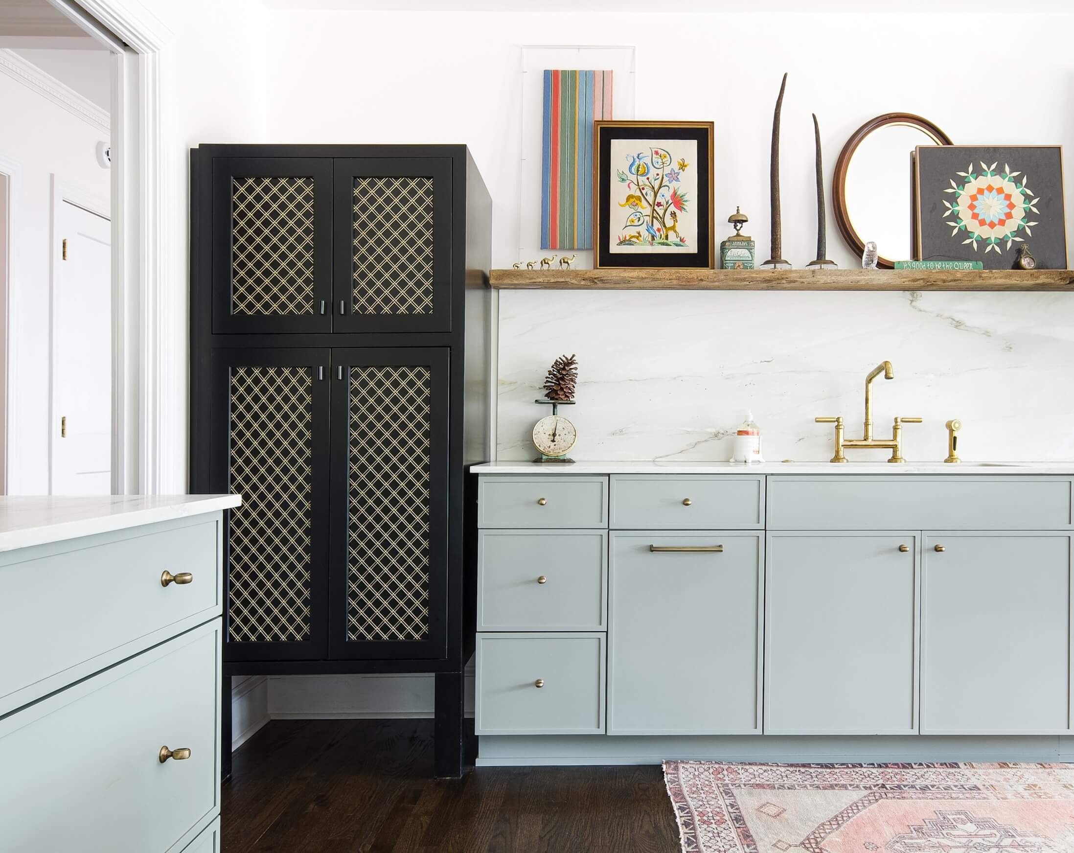 This free standing, black painted custom cabinet features decorative wire mesh cabinet door inserts that add texture and visual interest to the space. The dark cabinetry and woven metal panels create a distinctive focal point that contrasts the light blue skinny shaker cabinets.