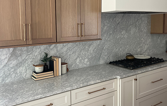 A two-tone kitchen design with light white painted cabinets and modern hood with light stained oak wood cabinets.